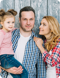 Family portrait with a father holding his daughter and a mother leaning in, emphasizing family unity and support in estate planning discussions.