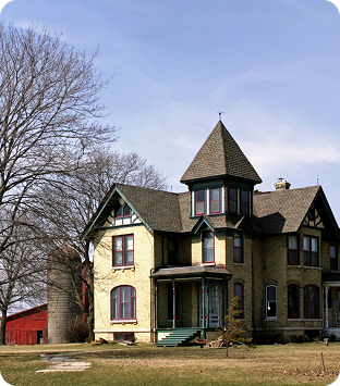 Victorian-style house with a turret, surrounded by trees and farmland, symbolizing family heritage and estate planning themes.