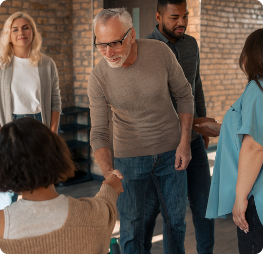 Group of people engaging in a welcoming interaction during an estate planning workshop, emphasizing community support and collaboration.