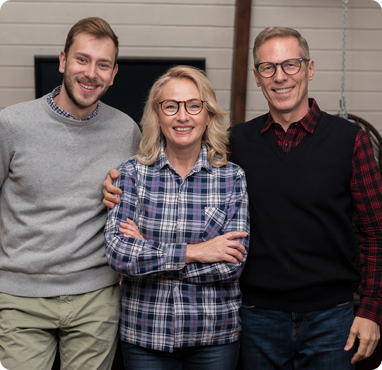 Three smiling individuals, representing a supportive community, standing together in a cozy indoor setting, promoting estate planning workshops and guidance from Legacy Peace.