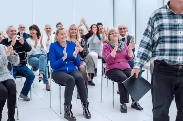 Audience applauding during an estate planning workshop, featuring engaged participants in a modern setting, highlighting Legacy Peace's educational focus.