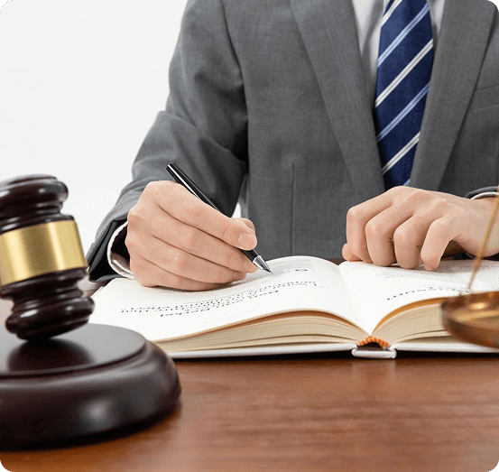 Person in a suit writing in a legal book with a gavel on a desk, symbolizing estate planning and legal education.